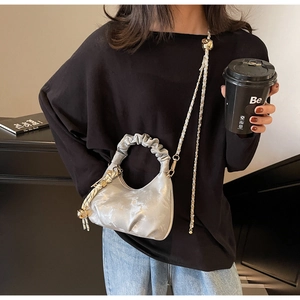 Chic silver pleated cloud bag with metallic finish shown on model in urban setting