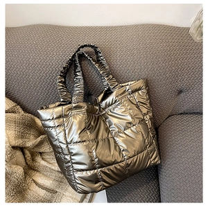 Close-up of metallic quilted tote bag with large square stitching on grey sofa