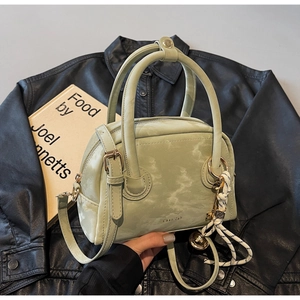 Detail of light green marbled handbag with braided key charm on black leather jacket