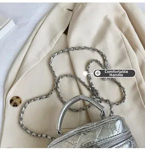 Gros plan du mini sac argenté matelassé avec chaîne sur tissu de blazer beige