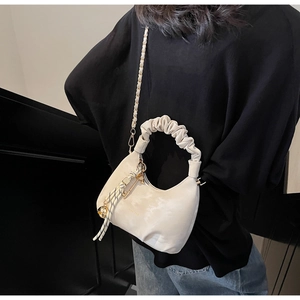 Detail of white crescent bag featuring pleated cloud handle and golden chain strap