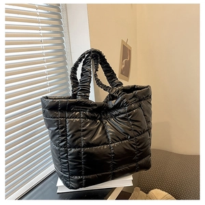 Detail of black quilted down tote bag with scrunchie handles and puffer texture