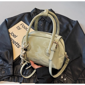 Detail view of a light green mini Boston bag with dual handles and long shoulder strap