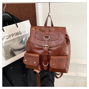 Détail d'un sac à dos vintage marron avec poches frontales et sangles à boucles