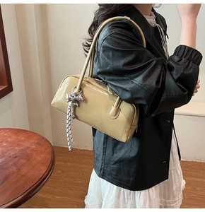 Détail de style d'un sac Boston jaune avec un nœud argenté et un charme rayé
