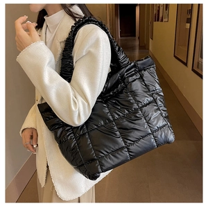 Detail of black quilted puffer bag showing the unique ruffled shoulder strap texture