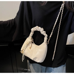 Detail of cream cloud bag with ruched handle, metal chain strap and decorative charms