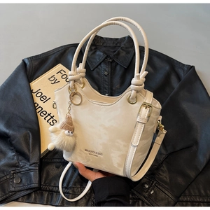 Detail of off-white tote bag with marble pattern, knotted handles and plush pendant