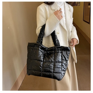 Close-up of black quilted puffer tote bag with glossy finish on a stylish model