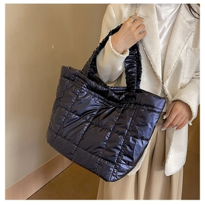 Detail of navy quilted puffer tote bag with ruffled handle worn by a model in casual attire