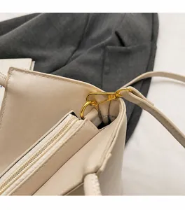 Detailansicht der beigen Eimertasche mit polierten goldfarbenen Beschlägen und Reißverschluss