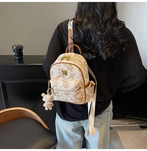 Detail van een mini-rugzak met berenprint in crème PU-leer met een schattige beerhanger