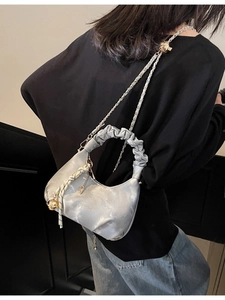 Silver pleated cloud bag with metallic chain and pearl luster finish on female model