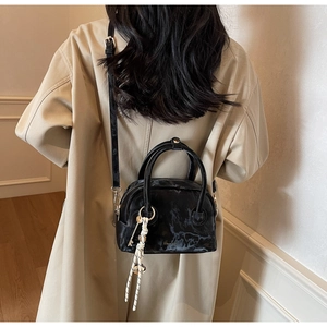 Detail of black marble textured crossbody bag with metal zipper and leather strap
