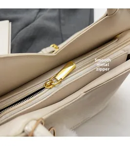 Détail de la fermeture éclair dorée lisse sur le sac à main en cuir beige crème