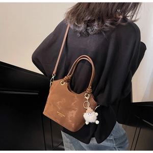 Detailed back view of a brown oil wax leather tote bag with a plush monster charm