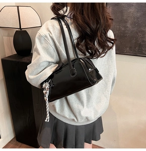 Détail du sac baguette noir brillant avec surpiqûres blanches et breloque coeur