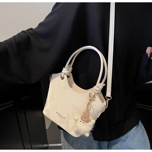 Detail of cream tote bag featuring V-cut opening and cute plush charm on model