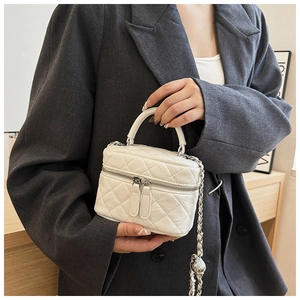 Sac vanité matelassé blanc porté par un mannequin vêtu d'un blazer gris très élégant