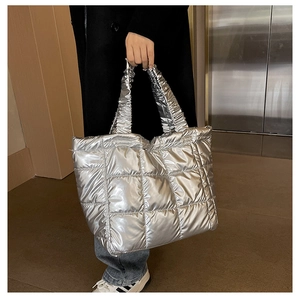 Detail of silver quilted tote bag featuring metallic finish and scrunchie handle texture
