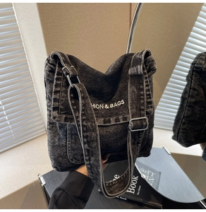Dettaglio della borsa a tracolla in denim nero vintage con ricamo di scritte bianche