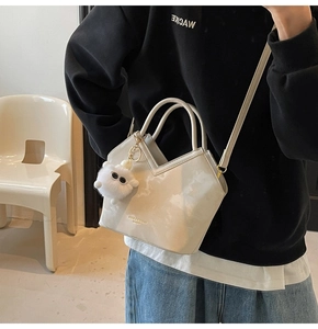 Détail du sac seau blanc cassé avec ouverture en V et charm ours en peluche