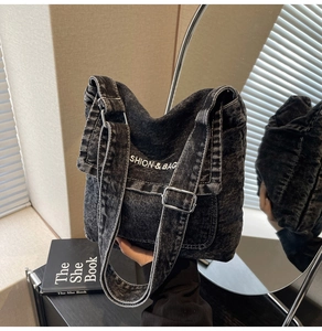 Dettaglio della borsa a tracolla in denim nero lavato con ricamo bianco e fibbia in metallo