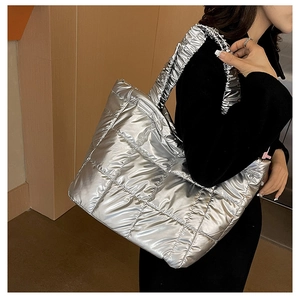 Detailed view of silver quilted down tote bag with metallic finish and wide shoulder strap