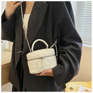 Détail du mini sac seau blanc matelassé avec bandoulière chaîne porté par un mannequin
