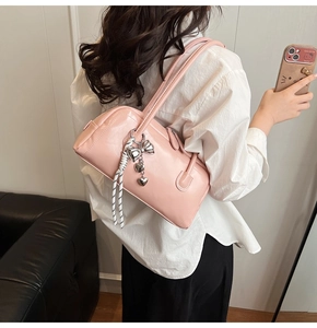 Sac Boston en similicuir rose avec nœud argenté et breloque cœur porté à l'épaule