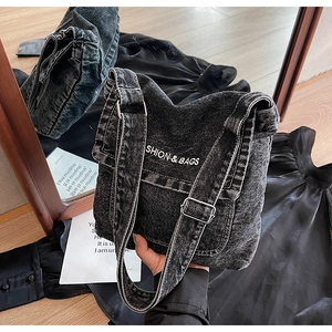 Dettaglio della borsa a tracolla in denim nero lavato con logo bianco e fibbia in metallo