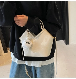 Détail du sac à main blanc cassé avec pendentif en peluche et ouverture en forme de V