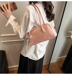 Détail du sac à bandoulière en cuir verni rose avec nœud argenté et breloque cœur