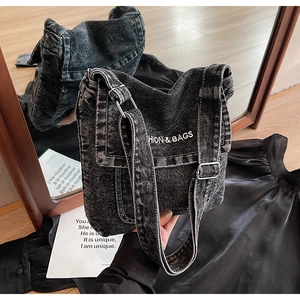 Dettaglio della borsa a tracolla in denim con ricamo bianco e fibbia di metallo argento