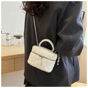 Détail d'un mini sac bandoulière blanc matelassé avec chaîne argentée et zips