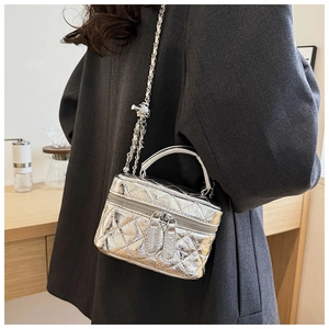 Détail du mini sac matelassé argenté avec bandoulière chaîne porté par un mannequin