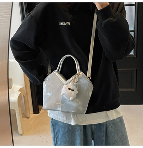 Détail du sac seau métallisé argenté avec ouverture en V et accessoire de charme en peluche