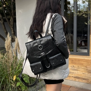 Sac à dos rétro en cuir noir avec deux poches frontales porté par un mannequin dehors