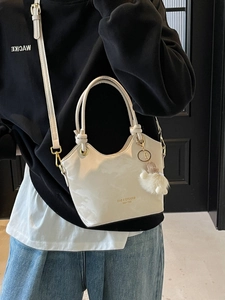 Minimalist cream tote bag in oil wax leather with double handles and plush pompom charm