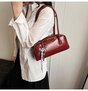 Détail du sac Boston bordeaux avec breloque nœud argenté et ruban à pois sur la lanière