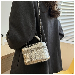 Détail du mini sac argenté matelassé avec bandoulière chaîne sur un blazer gris