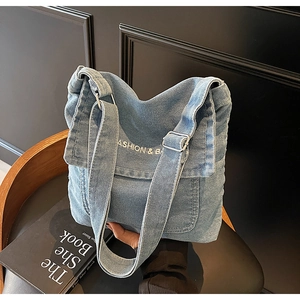 Dettaglio borsa a tracolla in denim azzurro con ricamo su una sedia di legno