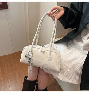 Détail du sac Boston blanc crème avec pendentif nœud argenté et double fermeture éclair