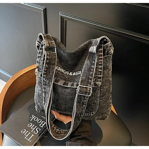 Dettaglio della borsa hobo in denim nero lavato con stampa di lettere e fibbia in metallo