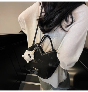 Détail du sac à main en cuir PU noir brillant avec ouverture en V et breloque peluche