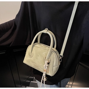 Close-up of mint green leather Boston bag featuring gold hardware and logo detail