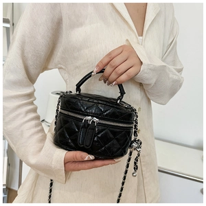 Détail du mini sac seau matelassé noir en cuir brillant avec sa chaîne argentée