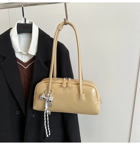 Détail du sac Boston beige en similicuir brillant avec un nœud argenté élégant