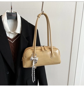 Détail du sac Boston beige avec breloque nœud argenté et doubles fines lanières