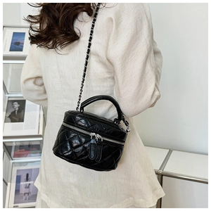 Mini sac seau matelassé noir avec bandoulière chaîne porté par un mannequin stylé